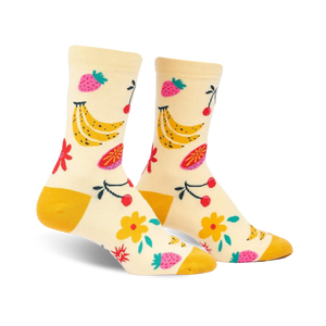 Cream crew socks with a playful fruit design. Bananas, strawberries, cherries, and flowers in yellow, pink, and red are featured on a light yellow background.