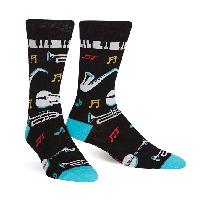 Pair of black crew socks with a jazz-themed design. Features musical instruments, notes, and piano keys, accented with teal at the cuff.