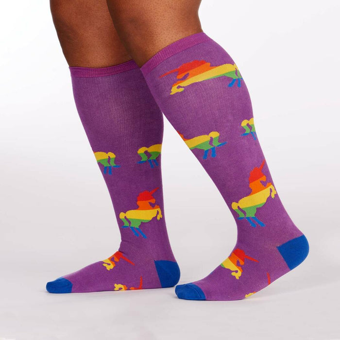 A pair of purple knee-high socks with a pattern of rainbow-colored unicorns.