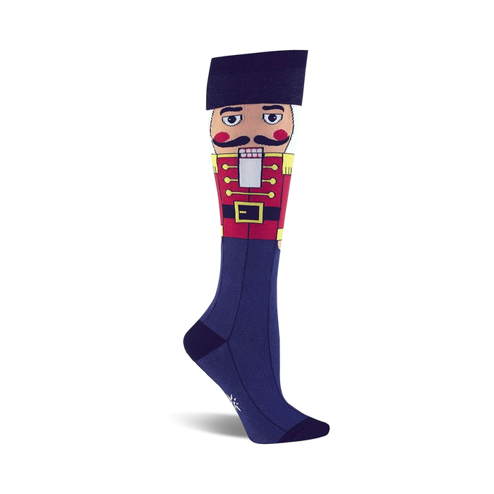 Knee-high socks in navy blue featuring a colorful Nutcracker design. The Nutcracker is depicted from the waist up, wearing a red coat and black hat. }}