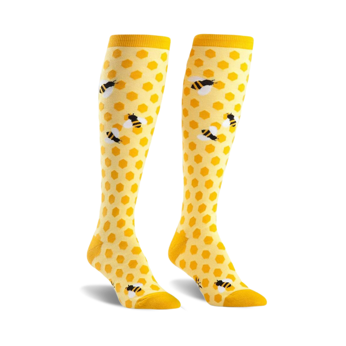 Pair of yellow knee-high socks with a honeycomb pattern and cute bee illustrations.