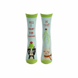 A pair of blue socks with a pattern of cartoon cats wearing Christmas hats and scarves. The left sock has the text 