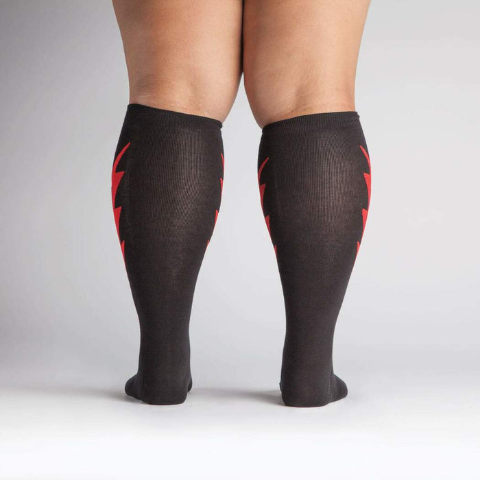 Rear view of a person wearing the black knee-high socks with red lightning bolts.