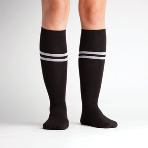 Studio shot: A pair of black knee-high socks with white stripes on a white background.