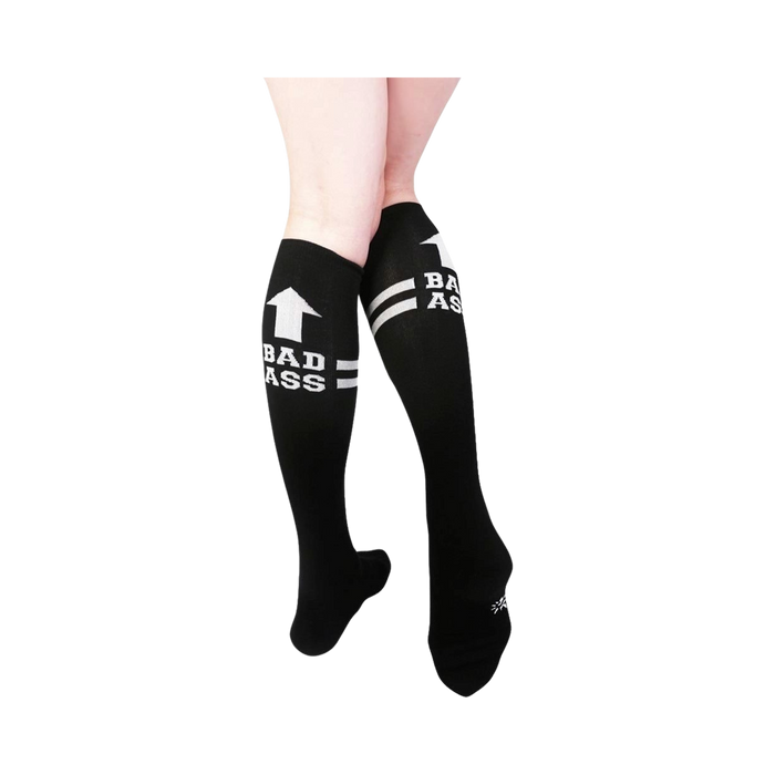 Pair of black knee-high socks with white stripes and 'Bad Ass' text.  Features an upward-pointing arrow graphic.