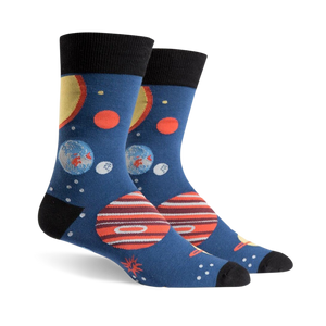 Pair of crew socks, navy blue with colorful planets, stars, and black cuffs. Fun space-themed design.