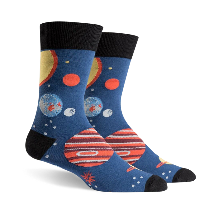 Pair of crew socks, navy blue with colorful planets, stars, and black cuffs. Fun space-themed design.