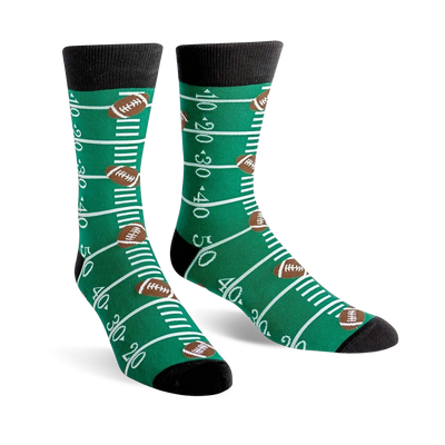 A pair of green crew socks with a football field design, including yard lines and brown footballs.