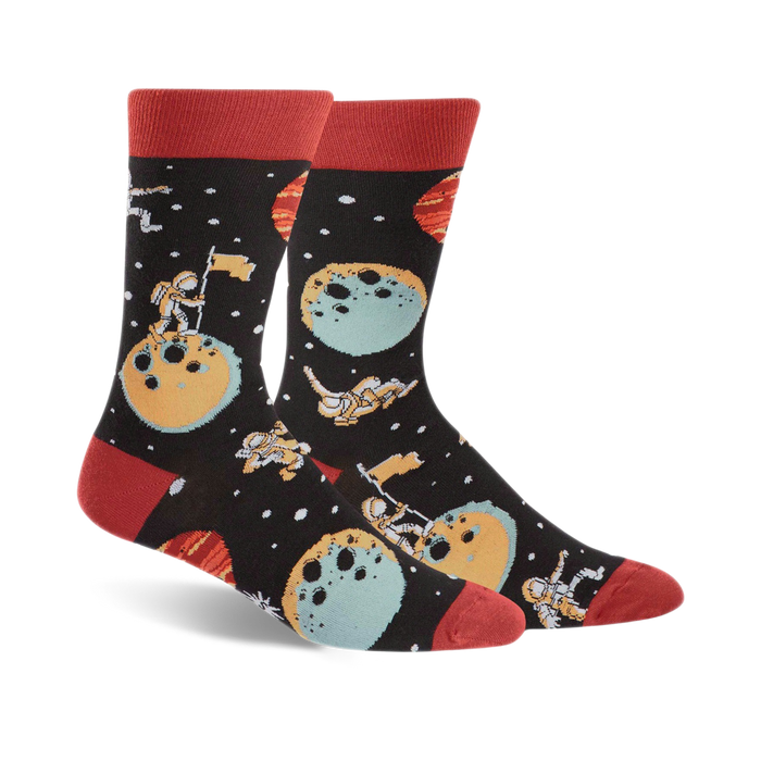 black-colored crew socks, featuring cartoon astronauts, moons, planets, stars in space design, with red toe and heel.    }}