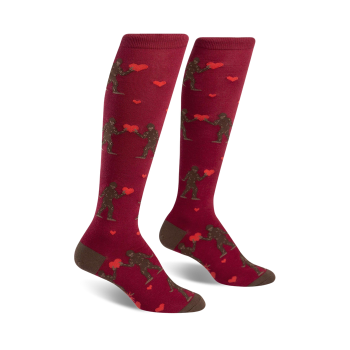 knee-high red socks with brown sasquatch holding red heart pattern.    }}
