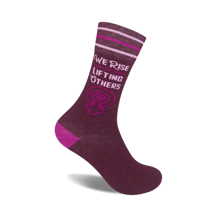 Burgundy crew socks with pink stripes and 'We Rise by Lifting Others' text alongside a feminist fist symbol. }}