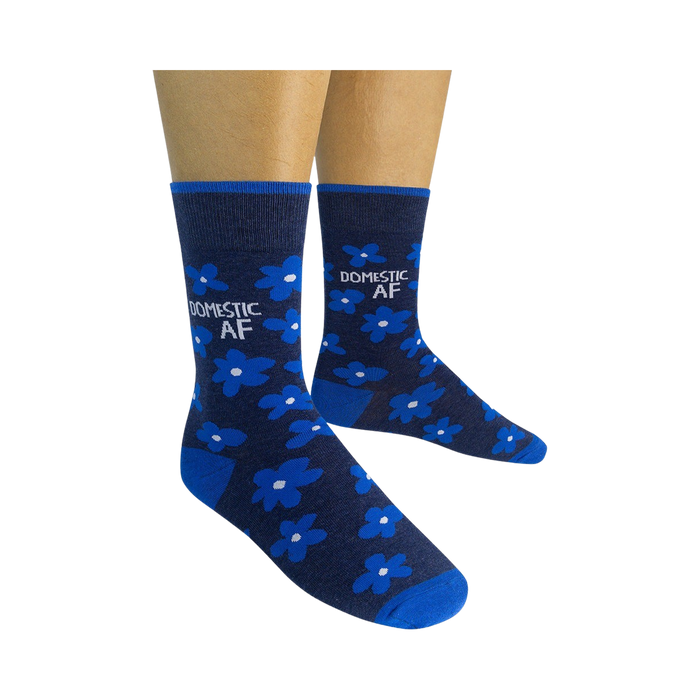 A pair of mid-calf socks with a dark blue background and a pattern of small white flowers. The socks have the words 