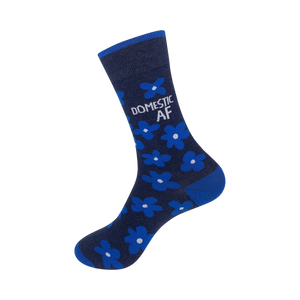 Close-up view of a navy blue crew sock showcasing the bright blue flower pattern and 'DOMESTIC AF' text.