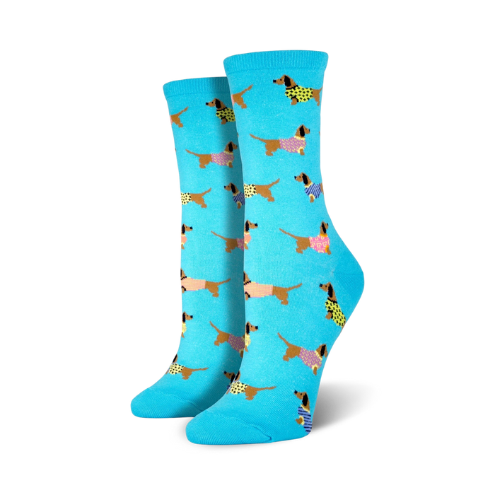 Pair of women's crew socks; light teal background with repeating pattern of brown dachshunds wearing colorful sweaters.