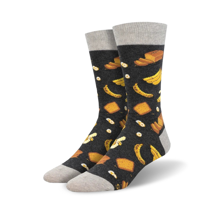 Pair of crew socks with a dark grey background and a whimsical pattern of yellow bananas and pieces of banana bread. }}