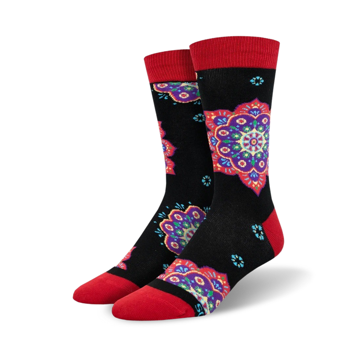 A pair of crew socks with a black background and colorful mandala designs in shades of purple, red, and teal. The socks have red cuffs. }}