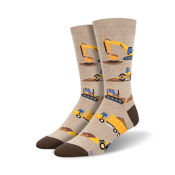 Beige crew socks with repeating illustrations of yellow construction vehicles like bulldozers, excavators, and dump trucks. Brown heel and toe. }}