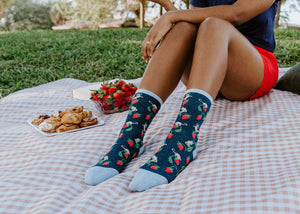 Lifestyle shot: Person wearing Berry Mice socks while enjoying a picnic outdoors.