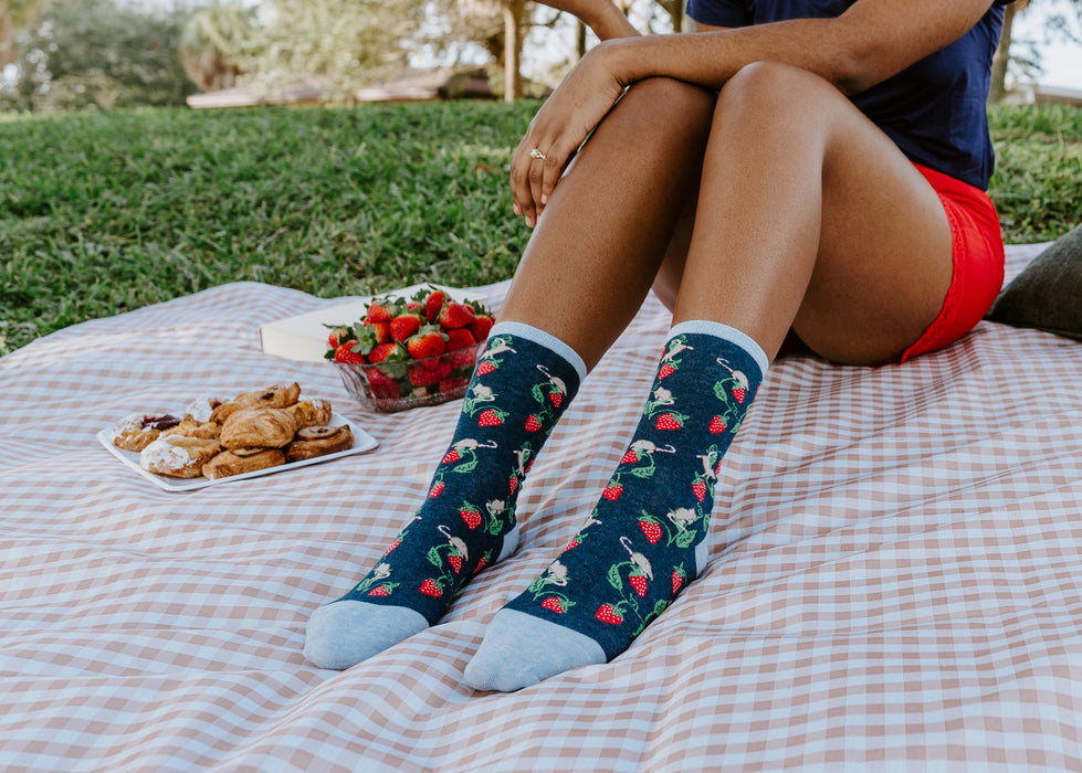 Lifestyle shot: Person wearing Berry Mice socks while enjoying a picnic outdoors.
