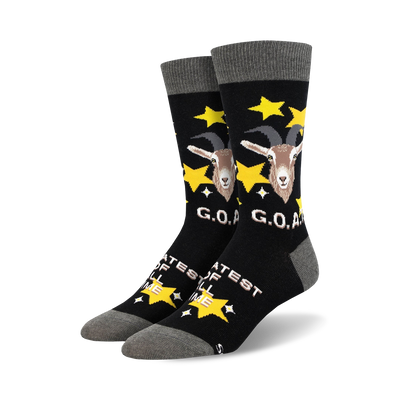 A pair of black crew socks with a goat design, gold stars, and 'G.O.A.T.' text.  The socks have a grey cuff.