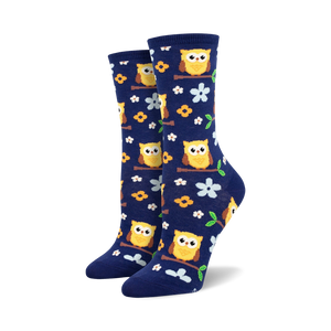 Pair of navy blue crew socks with yellow owls and flowers. Lifestyle shot showing socks with white sneakers.