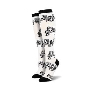Pair of black and white knee-high socks with a musical notes and clef design.