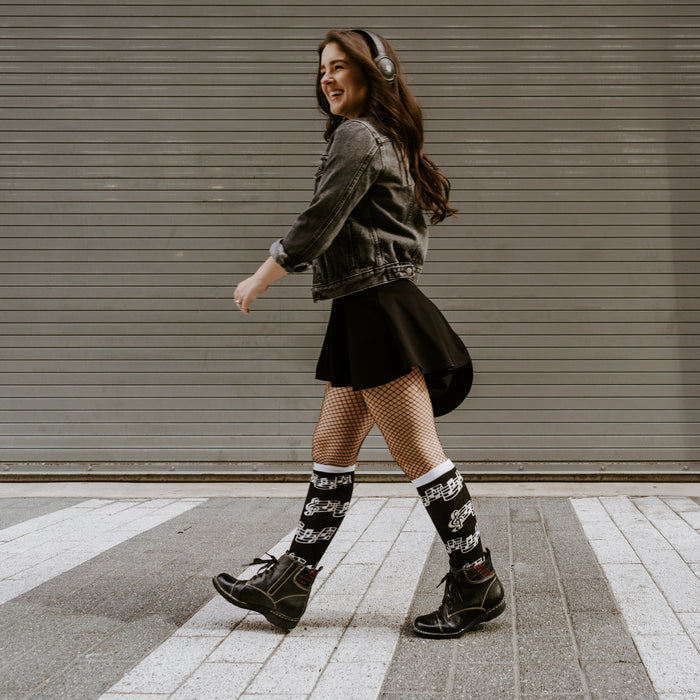 Lifestyle shot: Woman walking while wearing black musical note socks.
