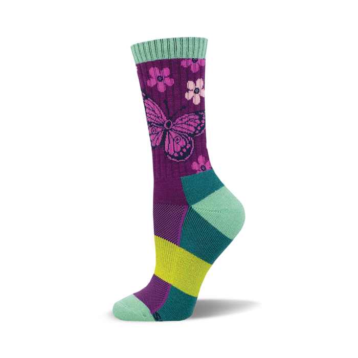 the sock is mostly dark purple with a light purple butterfly. the butterfly's wings have a dark purple outline and light purple and pink flowers with light green leaves. the sock also has light green, teal, and yellow accents at the top and bottom. }}