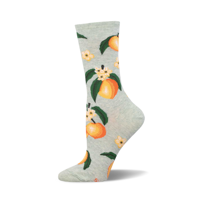 A pair of light green crew socks adorned with a repeating pattern of ripe peaches, green leaves, and delicate white flowers. }}