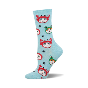 An upright light blue crew sock patterned with grey and white cats in red crab and green frog hats.