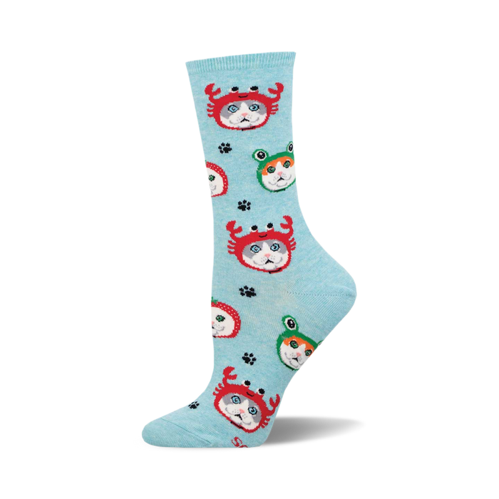 An upright light blue crew sock patterned with grey and white cats in red crab and green frog hats.