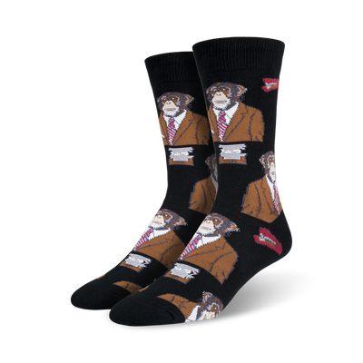 A pair of black crew socks with a repeating pattern of monkeys wearing brown suits and red ties. Small red lips are also part of the design.