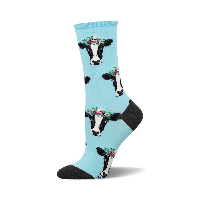 Crew socks featuring a light blue background and repeated pattern of black and white cows wearing flower crowns.