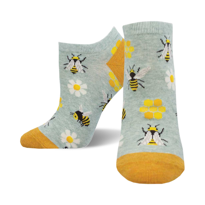 socks with a pattern of bees, beehives, and flowers on a blue background. the bees are black and yellow, the beehives are yellow and black, and the flowers are white with yellow centers. }}