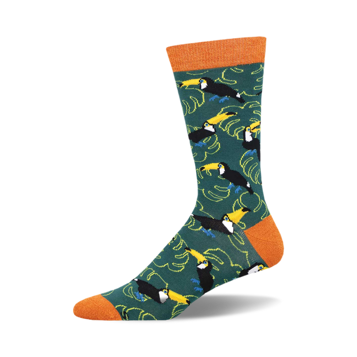 socks with a pattern of toucans, leaves, and bamboo. the toucans are black, yellow, and blue with orange feet and they are standing on branches of bamboo. the leaves are green with yellow and orange veins. the background is dark green. }}