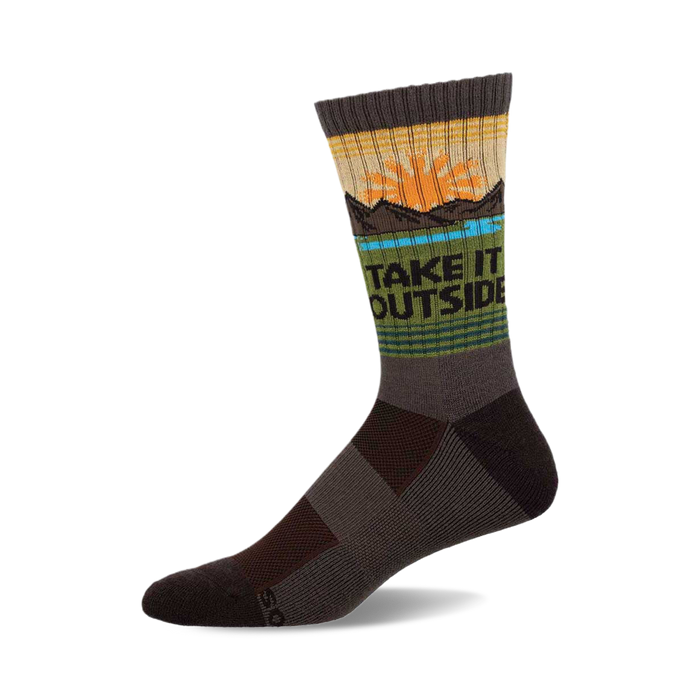A crew wool sock in dark brown, olive green, and tan, showing a sunset and mountain graphic with the text 'TAKE IT OUTSIDE'. }}