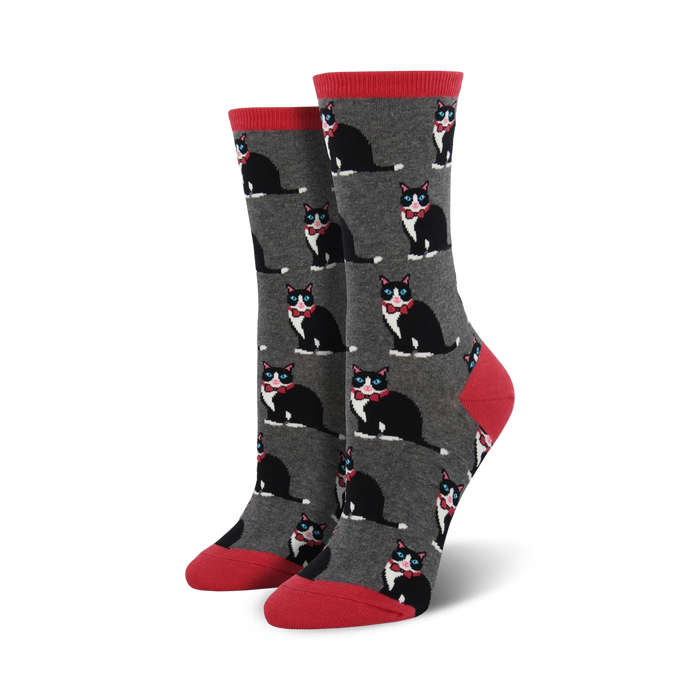 A pair of women's crew socks in gray with a repeating pattern of black tuxedo cats wearing red bow ties. The socks have coral red cuffs. }}
