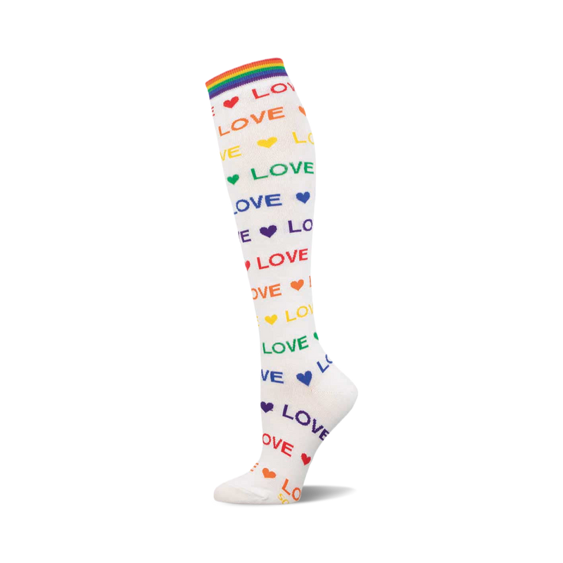 White knee-high sock with rainbow 'LOVE' text, colorful hearts, and a rainbow striped cuff. Shown on a white background.