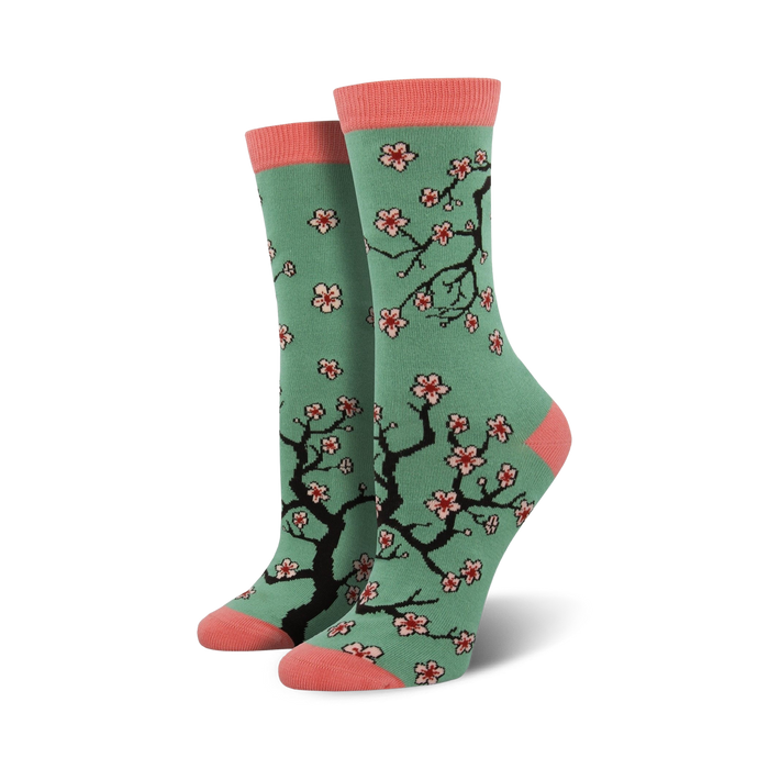 Crew socks in teal with a pink toe and heel. Features a repeating pattern of black cherry blossom branches and pink flowers. }}