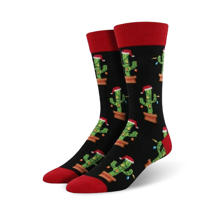 Pair of crew socks; black background with repeating pattern of cacti wearing Santa hats and Christmas lights; red cuffs. }}
