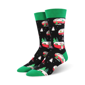 A pair of crew socks with a black background, featuring red and white Christmas camper vans, snowmen, and Christmas trees. Green cuffs.
