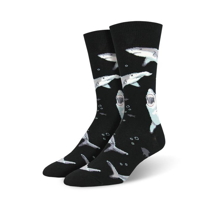 Pair of crew socks; black and teal sharks swimming on black or royal blue background. Fun and playful design.
