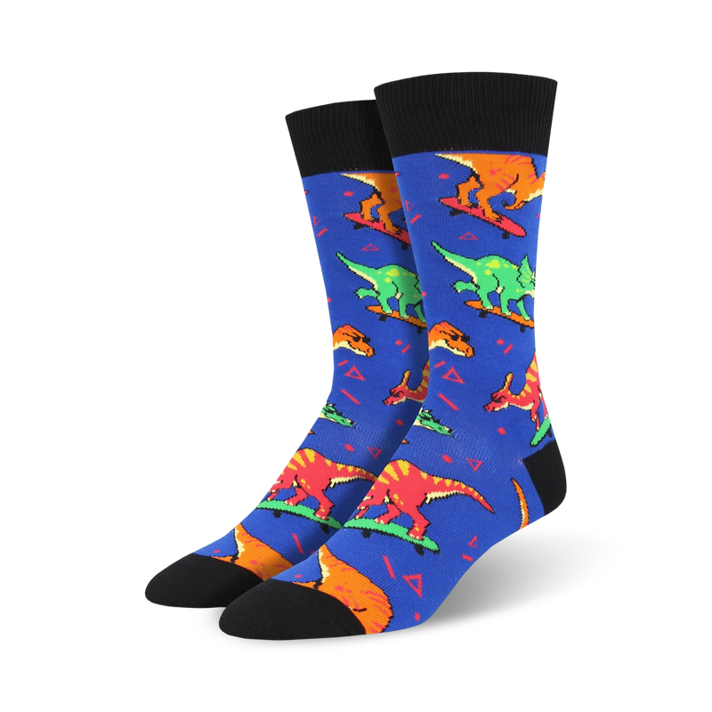 A pair of blue crew socks with a fun pattern of colorful dinosaurs skateboarding. The socks have black cuffs and a 90s-inspired design.