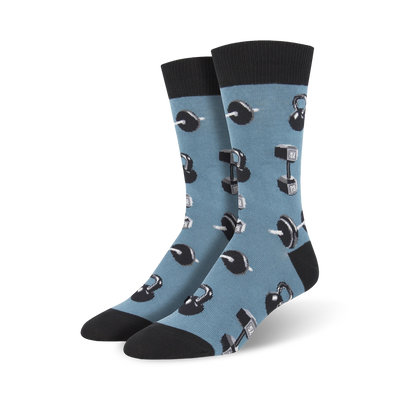 A pair of men's crew socks in blue with a pattern of grey kettlebells and dumbbells. Black cuffs complete the look.