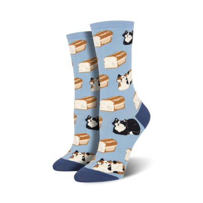 A pair of women's crew socks in light blue. The socks feature a pattern of calico and black cats lounging on loaves of bread.
