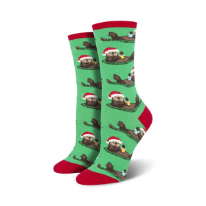 Pair of women's crew socks. Green background with repeating pattern of otters wearing Santa hats and holding gifts. Red and teal accents.