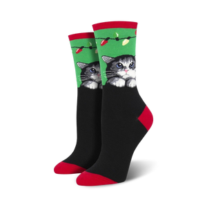 Pair of women's crew socks. Black background, green and red accents, cute gray cat peeking over the top with holiday lights.