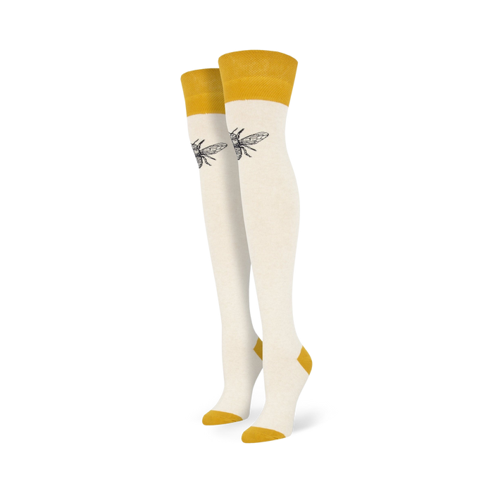 Pair of off-white knee-high socks with mustard yellow cuffs and a small, dark bee graphic on each sock.