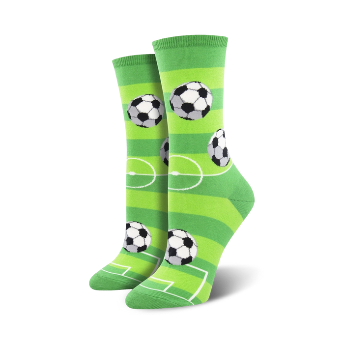 Pair of women's crew socks with a soccer field design. The socks are lime green with white stripes and black-and-white soccer balls. }}