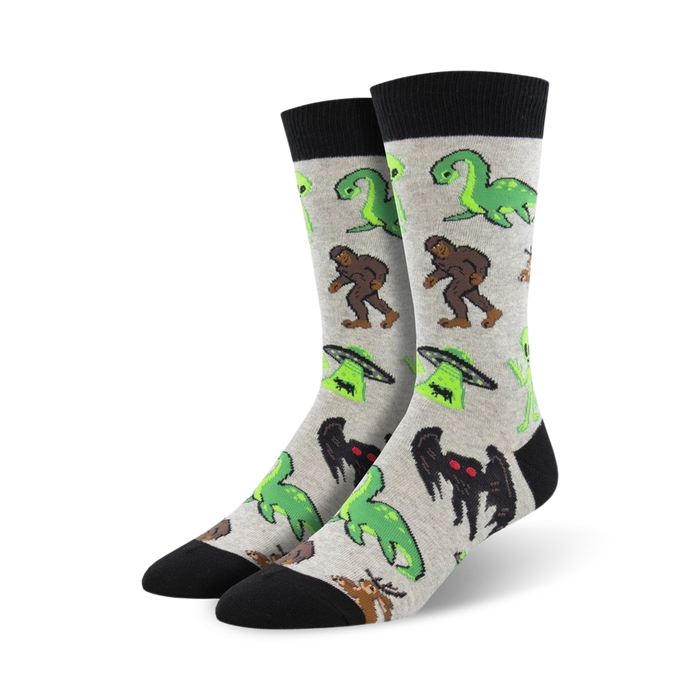 Pair of crew socks in grey and black, featuring a fun print of various cryptids including Bigfoot, Nessie, and aliens.